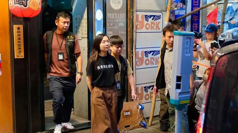 A polícia escolta uma funcionária para fora da livraria Have a Nice Stay, cuja camiseta dizia "Sou funcionário de uma livraria"
